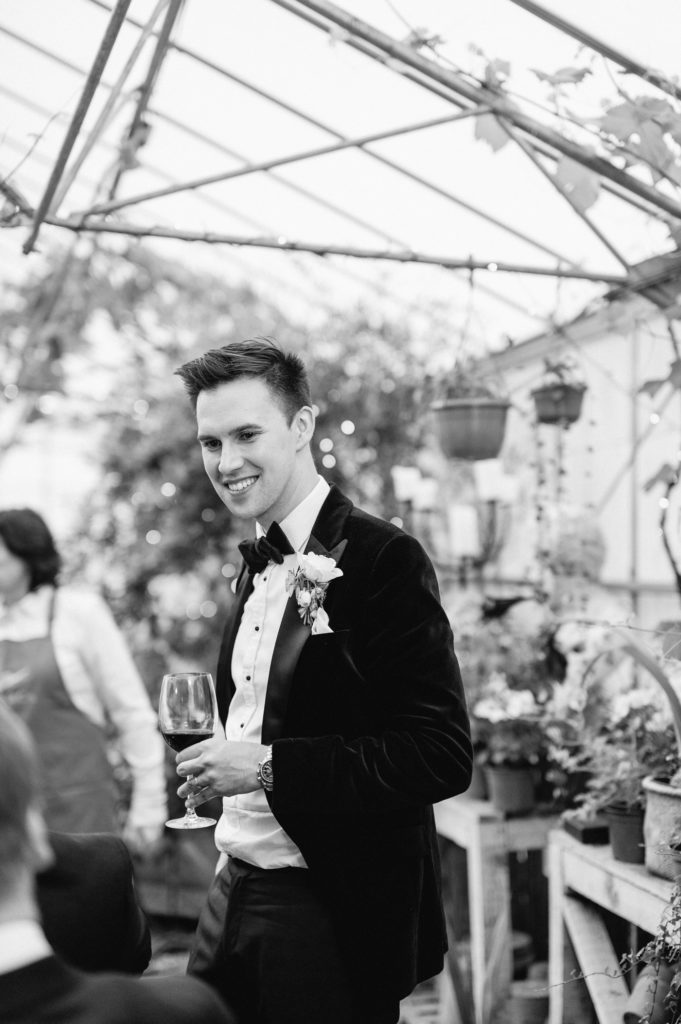 groom during wedding reception holding glass of red wine