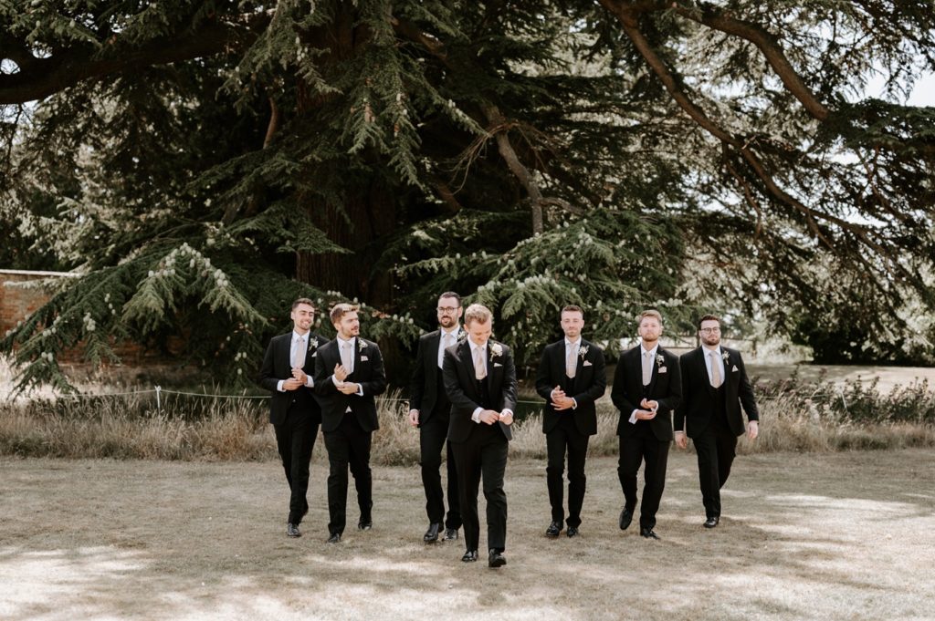 groomsmen walking wearing black suits