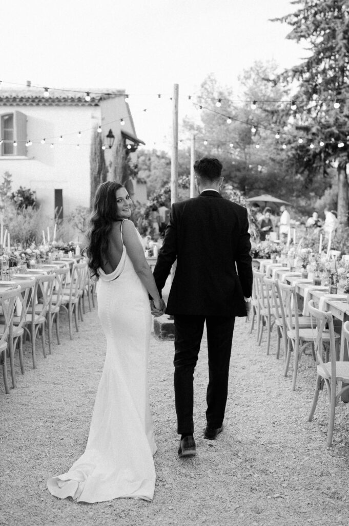 bride and groom walking through courtyard wedding reception setup at le mas des costes