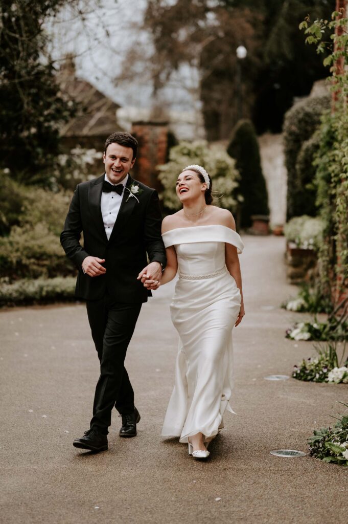bride and groom laughing walking at the orangery maidstone Kent wedding venue