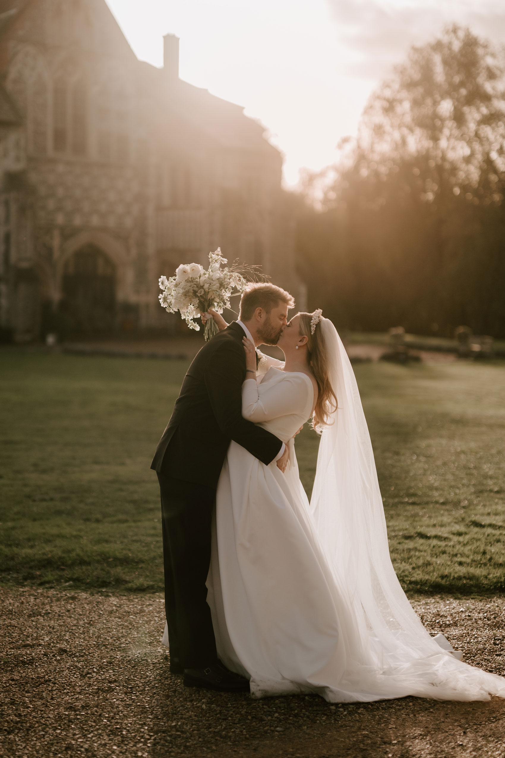 bride and groom portrait at sunset with butley priory in the background