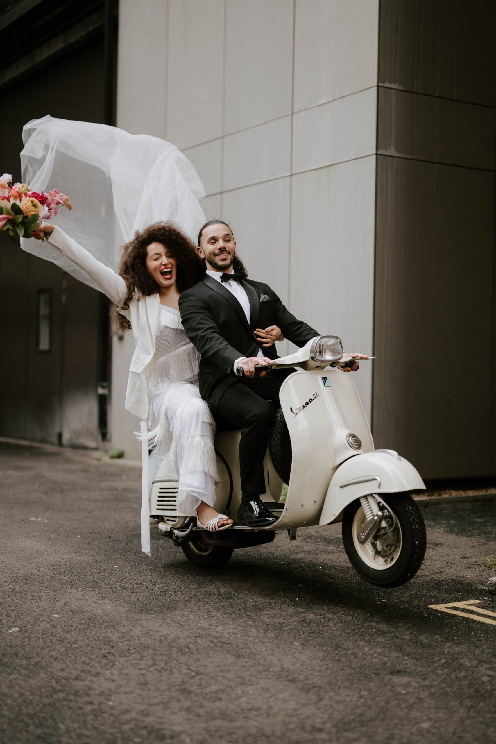 bride and groom riding vespa down streets of london