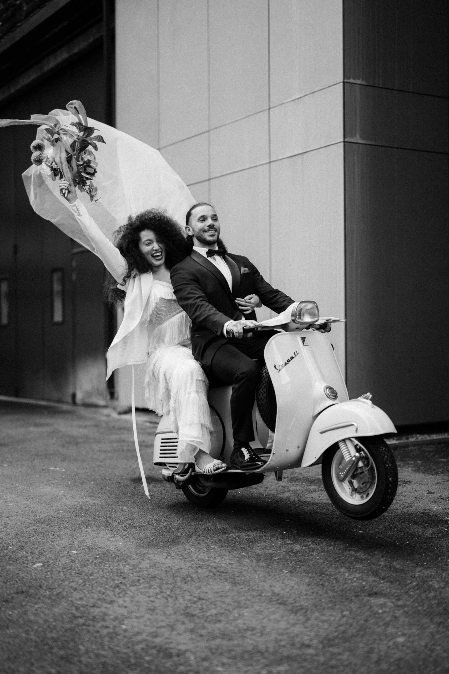 bride and groom riding vespa down streets of london