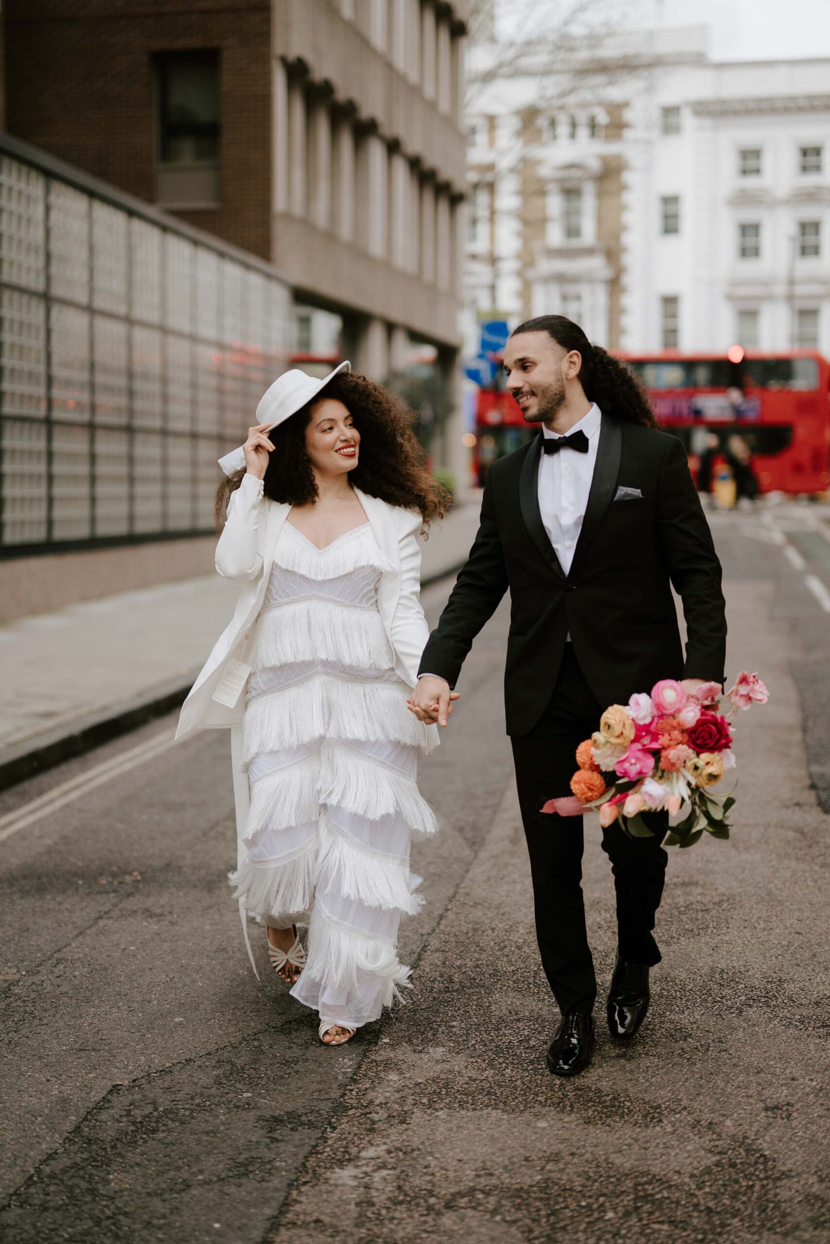 bride and groom walking down street with london bus in background