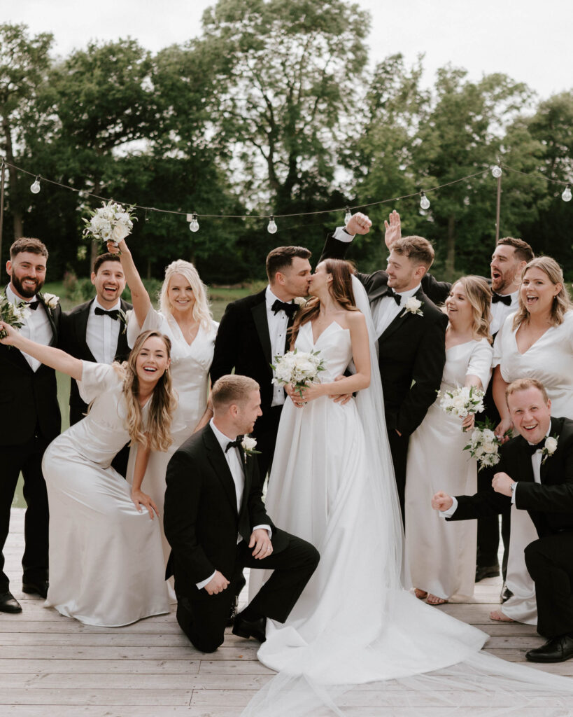 bridesmaids wearing white dresses and groomsmen wearing black tie at barns and yard