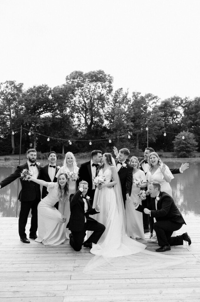 bridesmaids wearing white dresses and groomsmen wearing black tie at barns and yard in front of lake