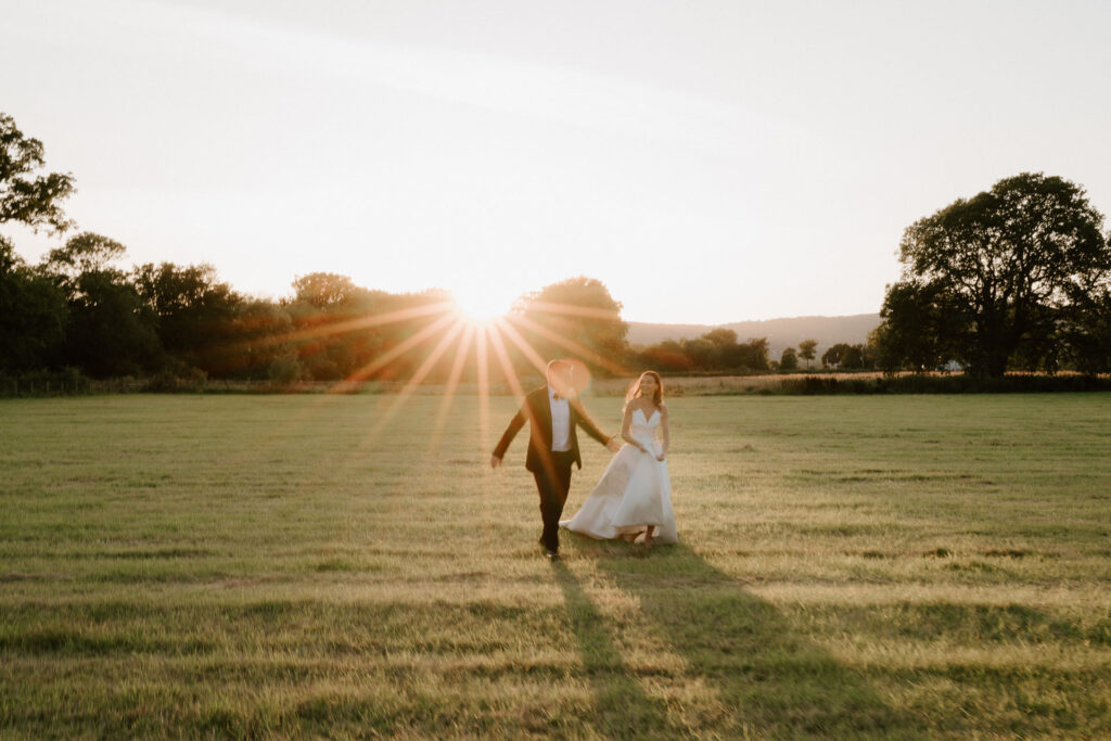 bride and groom at barns and yard running at golden hour