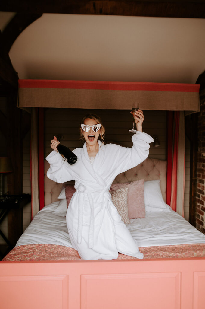 bride on bed with white sunglasses and champagne