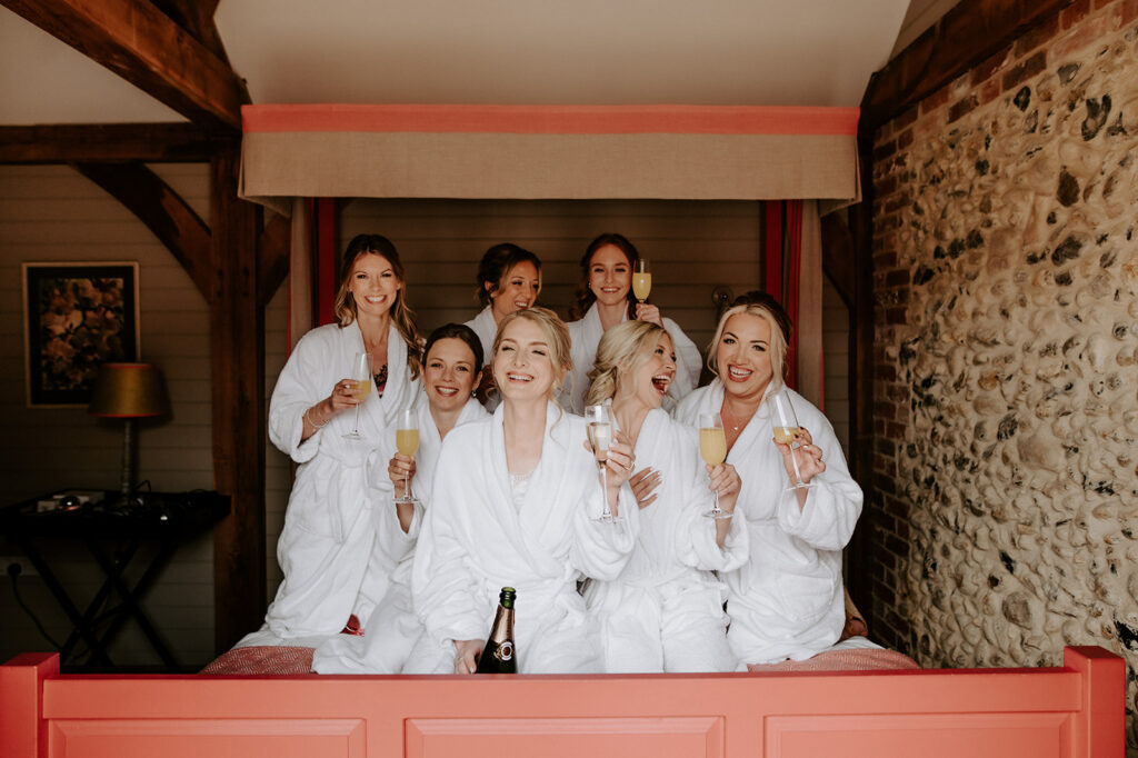 bride in dressing down with bridesmaids on bed at retreat east