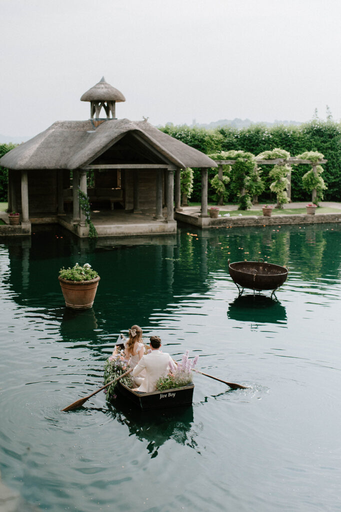 bride and groom in boat on lake at euridge manor in cotswolds