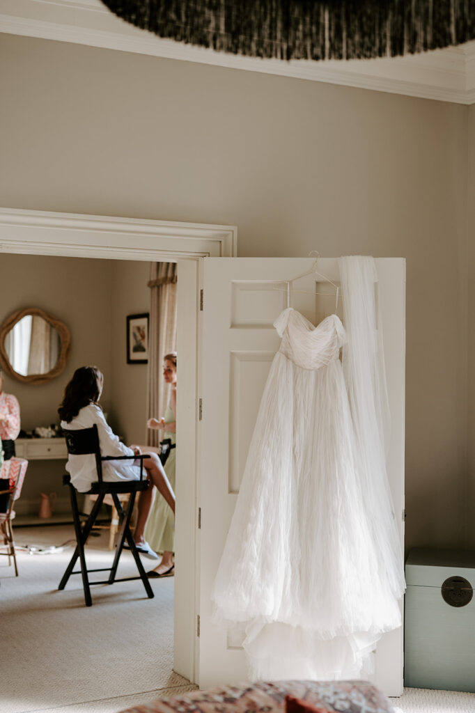 wedding dress with bride getting ready in background