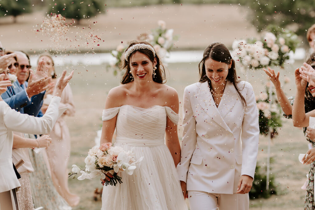 two brides walking back down aisle with confetti