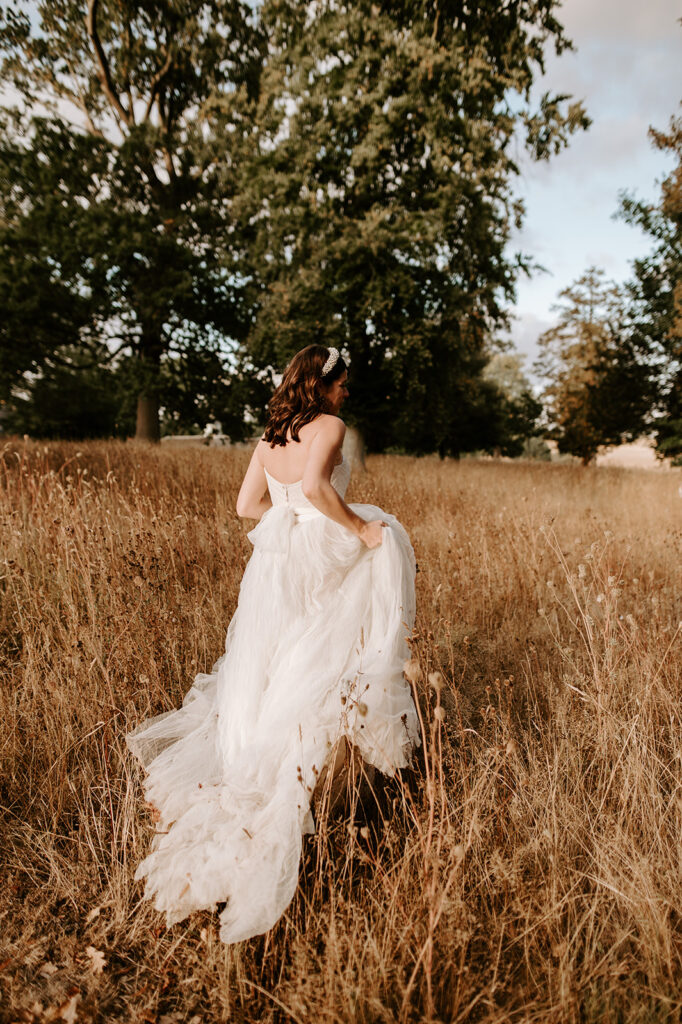 bride with white wedding dress walking into field