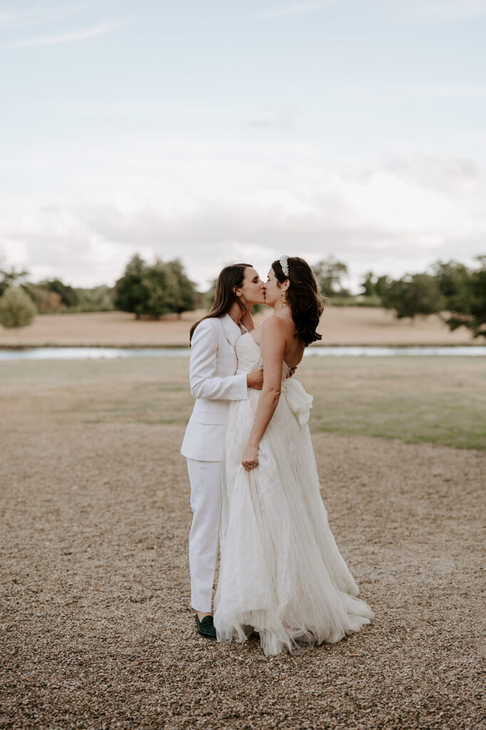 two brides kissing at wilderness reserve with lake backdrop