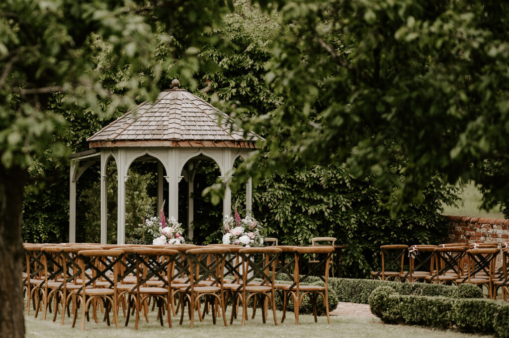 outdoor wedding ceremony set up at retreat east with flower urn arrangment and cross back chairs
