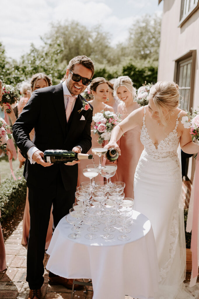 bride and groom pouring champagne into champagne tower at retreat east