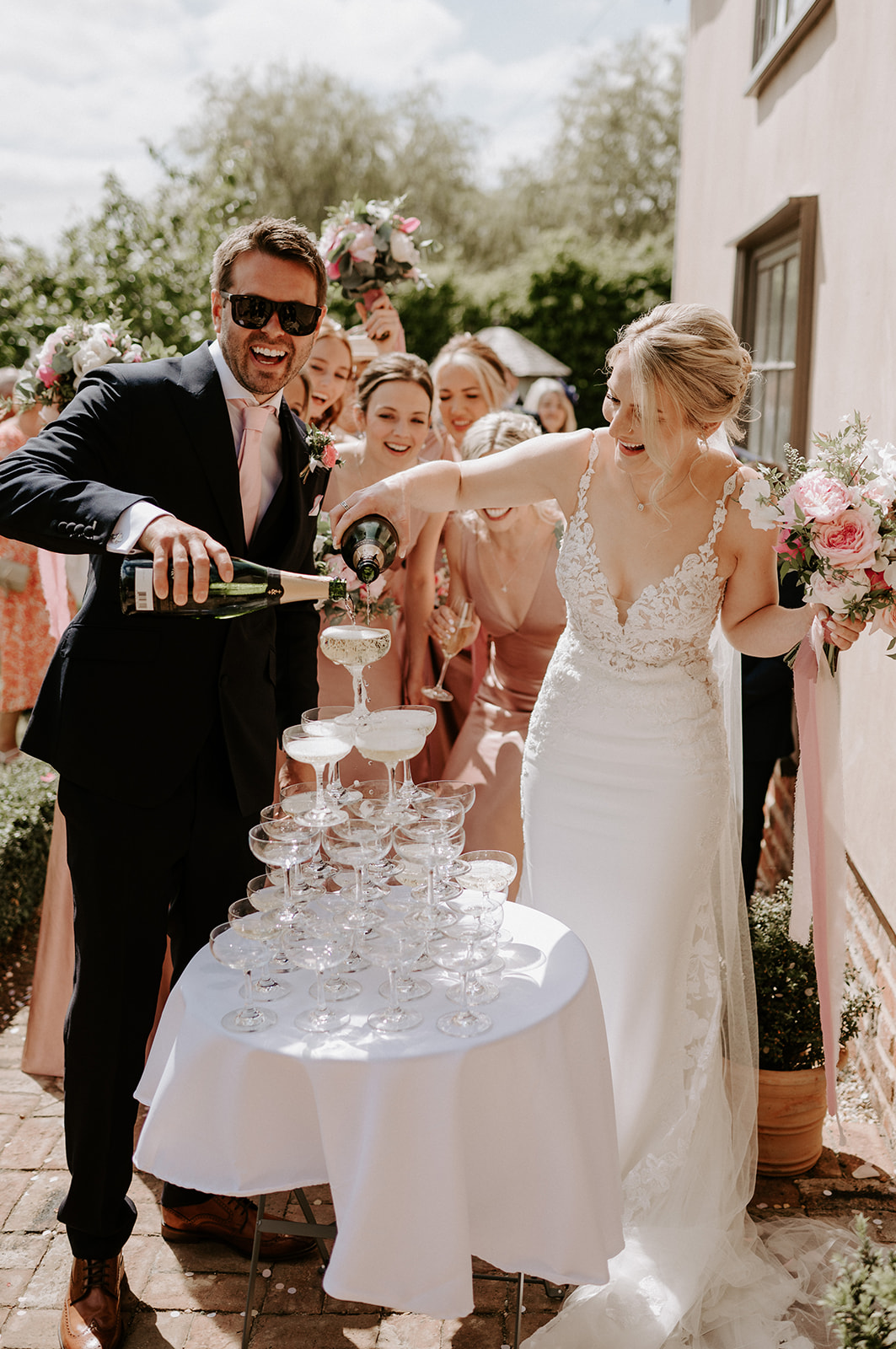 couple pouring champagne into champagne tower at retreat east wedding venue