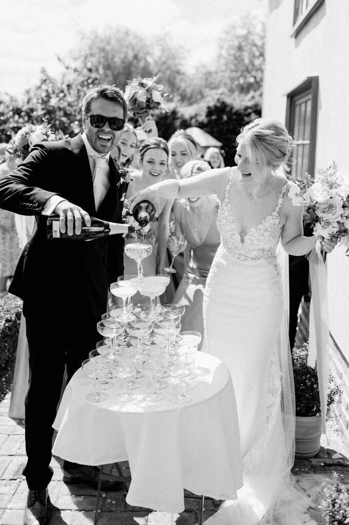 bride and groom pouring champagne into champagne tower at retreat east