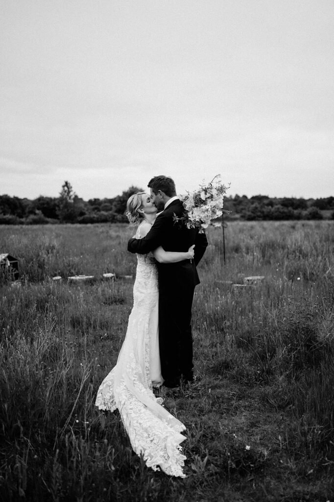 couple standing and sharing a kiss in field at retreat east