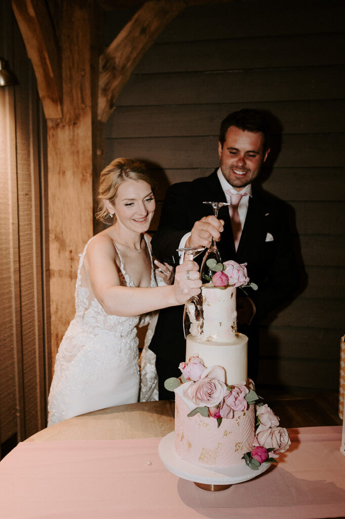 couple cutting cake in the great barn at retreat east