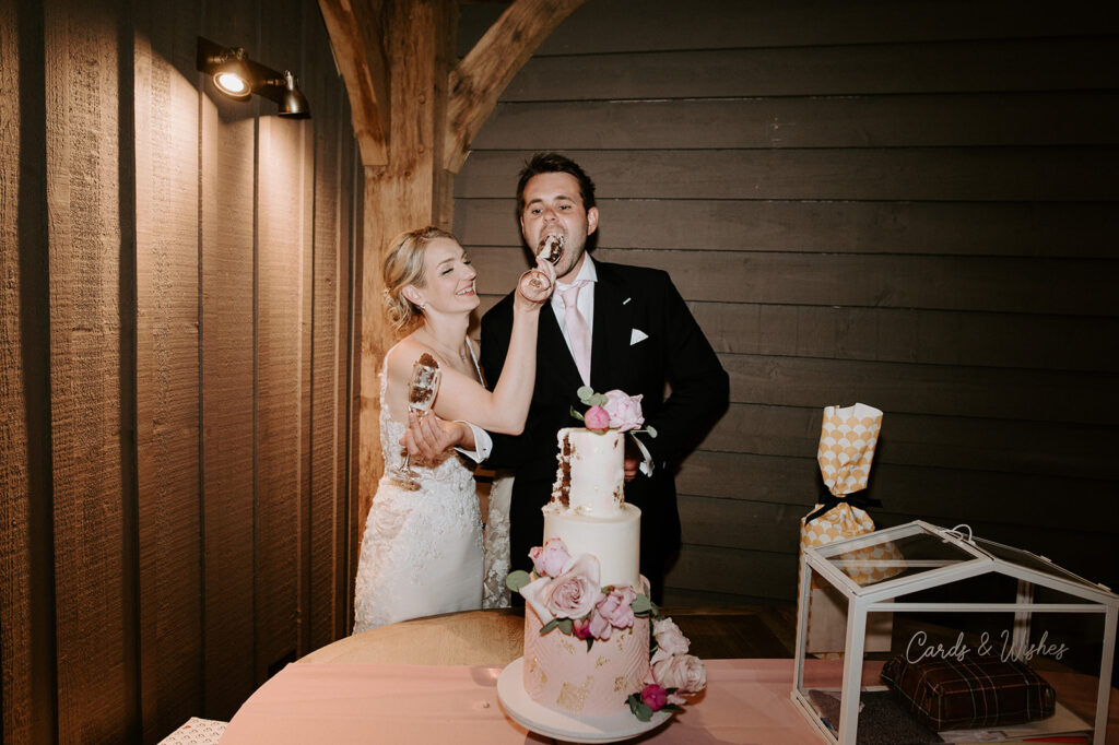 couple cutting cake in the great barn at retreat east