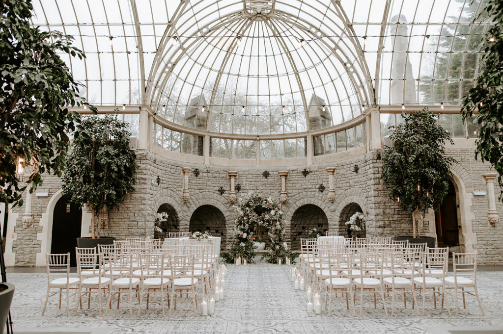 ceremony in the orangery at tortworth court with candles in aisle and floral arch