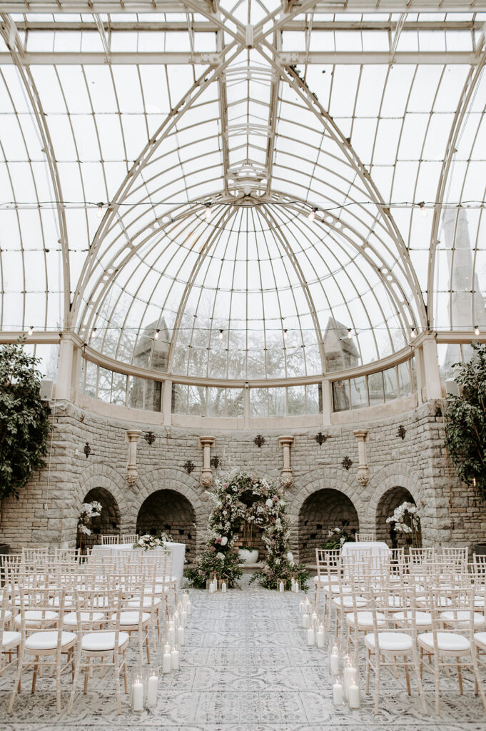 ceremony in the orangery at tortworth court with candles in aisle and floral arch