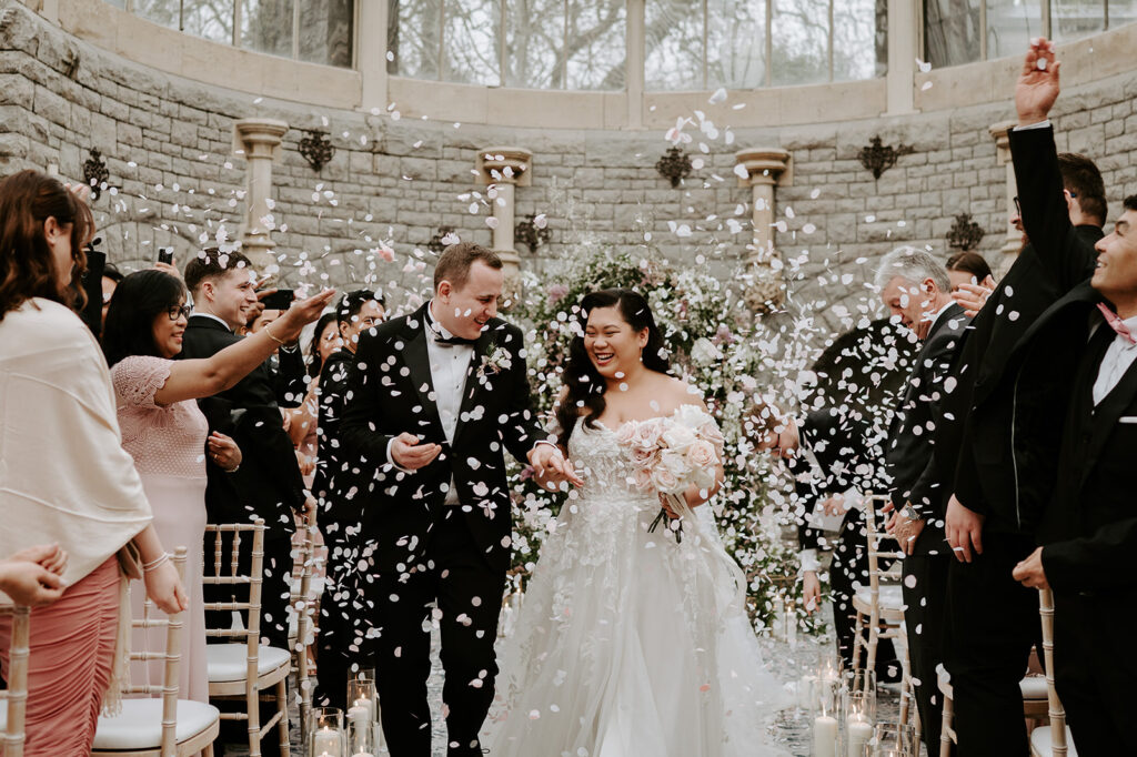 bride and groom walking through white confetti 