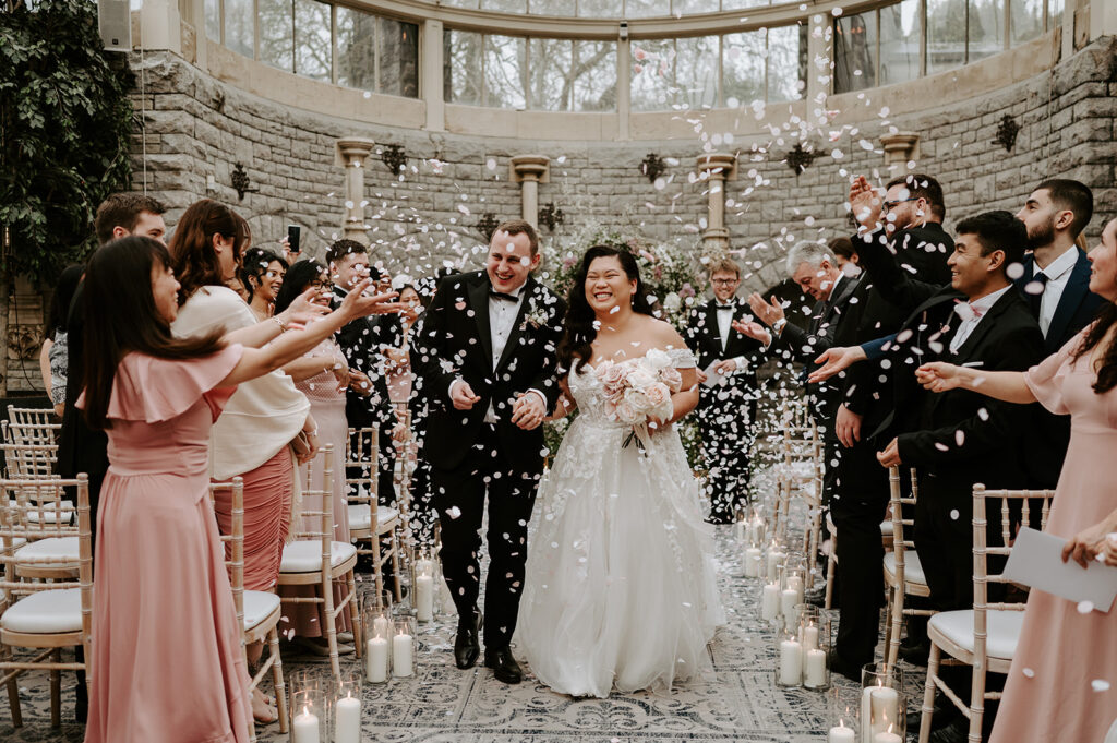 bride and groom walking through white confetti 