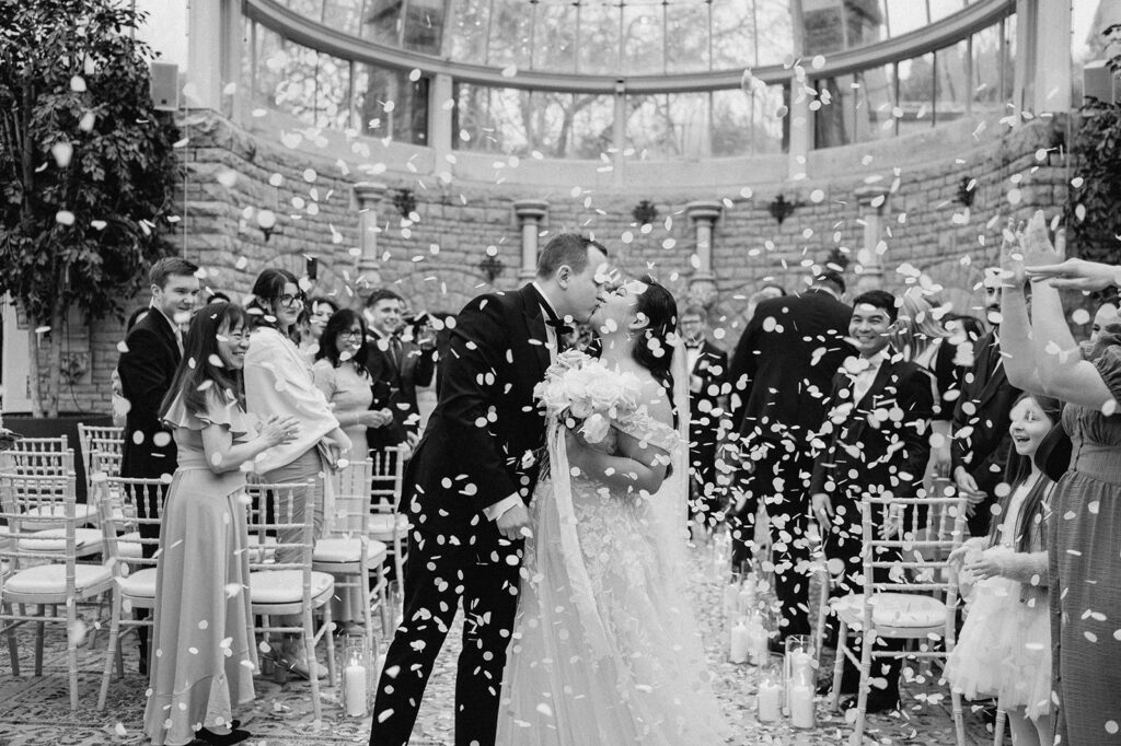 bride and groom kissing with white confetti 