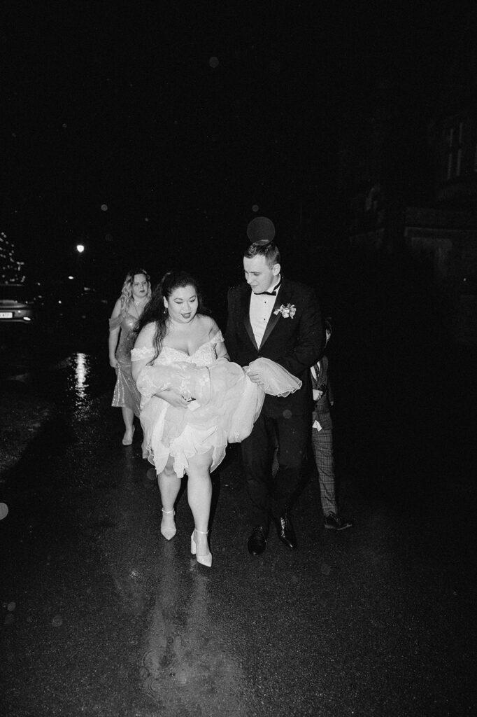 bride and groom walking in the rain at nighttime